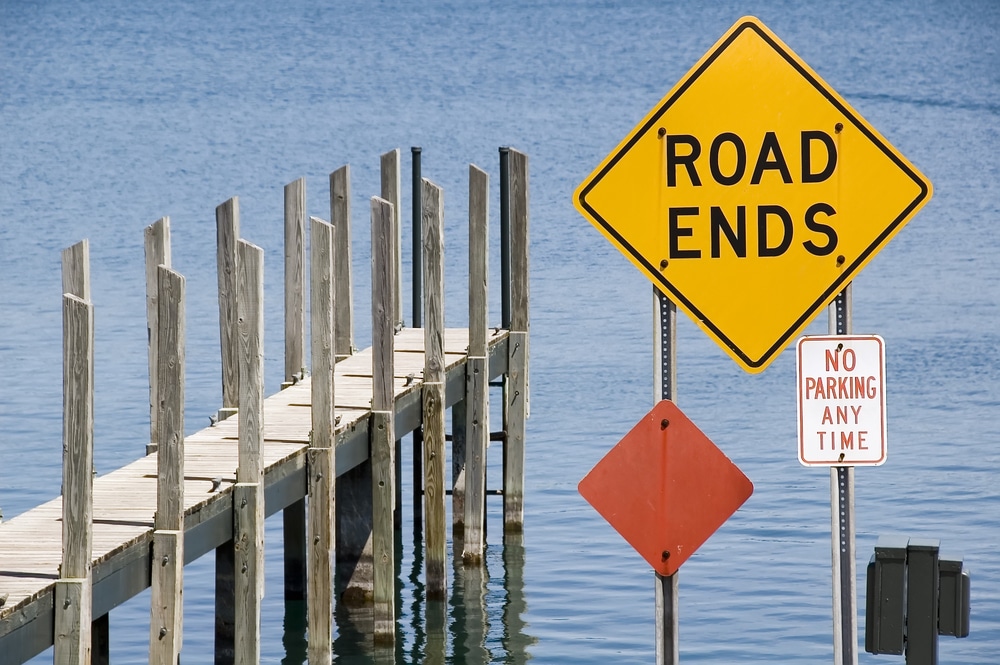 Pier and yellow ROAD ENDS sign by water